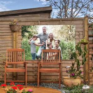 Er hangt een Canvas Company Tuinposter met familieportret in de tuin.